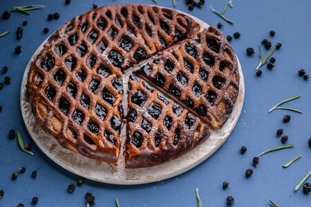 Close-up homemade open cake with black currant on a dark blue background.
