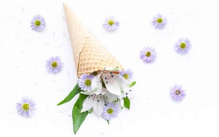 Top view wedding or catering decor. White alstromeria flowers in a waffle cone on a floral pattern. For decorating a wedding card or Valentines Day. Close-upの写真素材