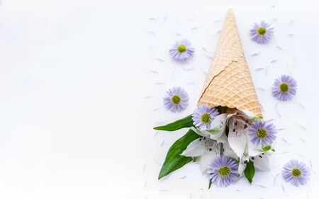 Top view wedding or catering decor. White alstromeria flowers in a waffle cone on a floral pattern. For decorating a wedding card or Valentines Day. Close-upの写真素材