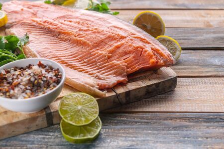 Close-up fresh appetizing salmon steak. Spices, lemon, fresh parsley and ice. Rustic background....