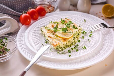 Close-up vegetarian lasagna with spinach and microgreens on a white plate. Tasty and healthy...