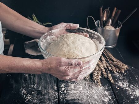 Female hands hold fermented homemade pastry for buns. Close-up. Step by step recipe