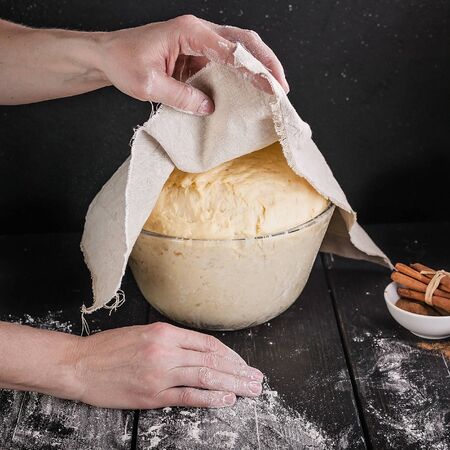 Female hands hold a napkin over a fermented homemade pastry for buns. Close-up. Step by step recipe