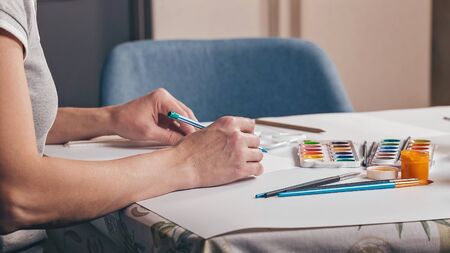 WEB banner format. Graceful female hands sketch in pencil on a white sheet of paper