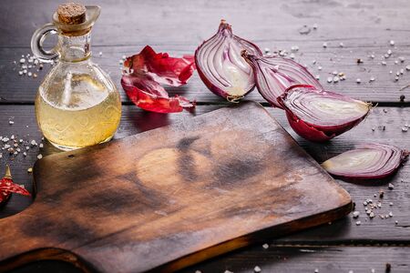 Wooden cutting board, red onions, hot peppers, spices and olive oil. Food still lifeの写真素材