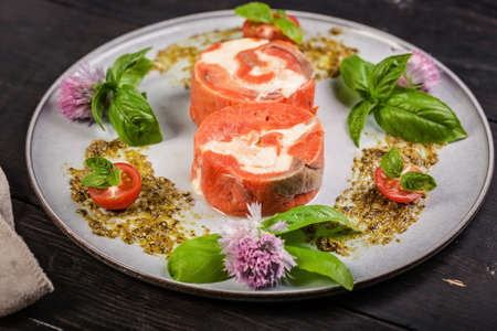 Appetizing pink salmon roll with cream cheese and shrimp meat with ricotta pesto sauce with fresh basil. Delicious seafood restaurant dishesの写真素材