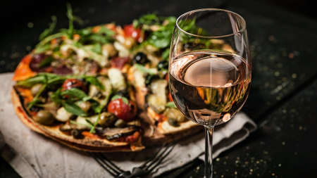 Glass of rose wine on background vegetarian pizza with mushrooms, eggplants, tomatoes, capers and fresh herbs. Food banner formatの写真素材
