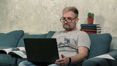 Caucasian middle-aged pensive man. Look directly into the camera. Holds glasses in his hands. Doubt....