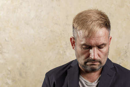 Caucasian middle-aged pensive man. Look directly into the camera. Holds glasses in his hands. Doubt....