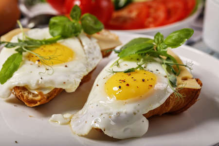 Close-up of fried eggs with spices, fresh basil and herbs on a white plate. Morning food still life....