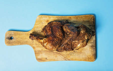 Food banner format. Half fried chicken on wooden cutting board on light blue background. Top view