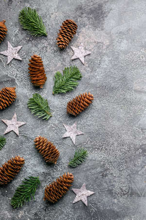 Vertical border of green fir branches, fir cones and stars on a gray-blue background. Christmas or...