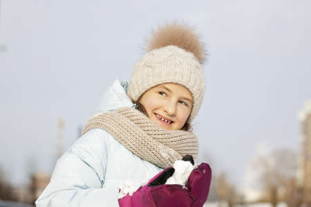 Winter portrait of a happy beautiful girl in a winter knitted hat. Girl holding snow. Lifestyleの写真素材