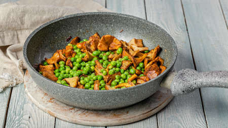 Food banner. Fried chanterelles with vegetables in a pan. Edible mushrooms and green peas. Vegeterian food.の写真素材