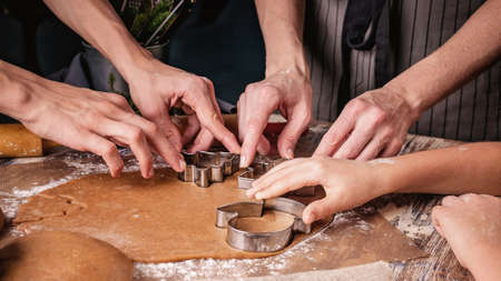 Mom and kids hands are preparing Christmas gingerbread cookies. Rustic table top background....