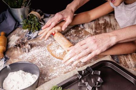 Mom and daughter hands hold a rolling pin. Molds and tools for baking homemade Christmas cookies....