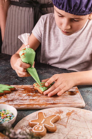 Girl decorate gingerbread cookies. Homemade traditional Christmas pastries. Delicious dessert. Hands...