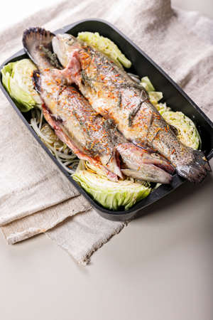 Fresh trout with spices and vegetables. Freshwater fish with saffron, red onion and cabbage in a...