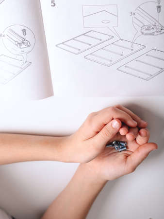 Hands of a caucasian girl are holding a furniture screws.の写真素材