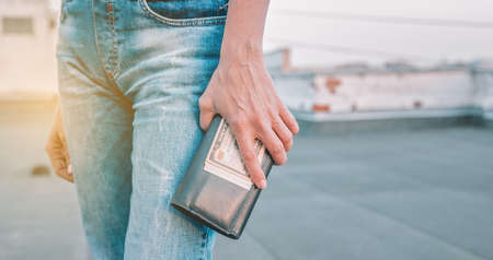 Female hands are holding a wallet with US dollars. The concept of finance, savings, financial...
