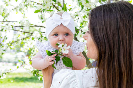 Happy family lifestyle photography. Smiling brunette mom and her little daughter in a blooming...