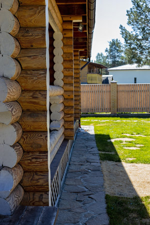 The facade of the modern wooden house made of round logs. Comfortable living, out-of-town rest and relaxation in nature. Suburban construction from natural materials. Side view. Vertical shotの写真素材