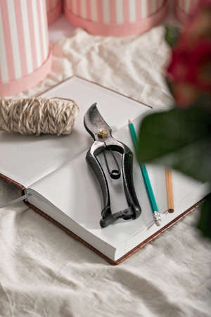 Florist workplace. Small business concept. Diary for order records, pencils, flower scissors. Flowers and accessories. Vertical shot. Copy spaceの写真素材
