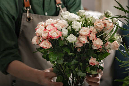 Florist is holding a large bouquet of roses. Florist workplace. Small business concept. Flowers and accessories shop. Close-upの写真素材