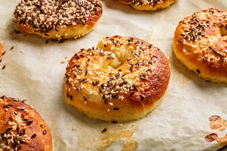 Fresh and crispy New York bagels with sesame seeds. Homemade baking. Hot bagels on baking paper. Cook at home. The best homemade New York-Style Bagel Recipe. Crusty sesame tasty buns. Close-upの写真素材