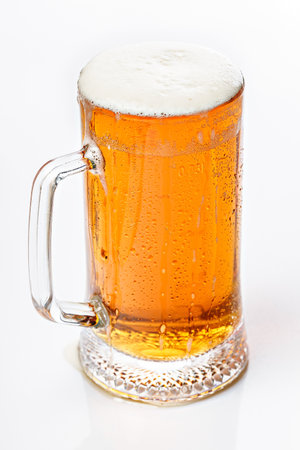 Close-up mug of cold light beer on a white background. Beer foam and bubbles. Vertical shot. Traditional light alcoholic drink shot.の写真素材