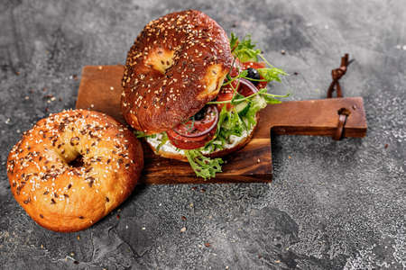 New York bagel with cream cheese, salad, cucumber, herbs, olives and salted red fish. Homemade sandwich salad on a cutting board. Excellent delicious breakfast or snack. Top view. Copy spaceの素材 [FY310171097907]