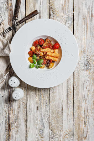 Traditional penne pasta with tomatoes, spices, Parmesan cheese and fresh basil. Dish of classic Mediterranean cuisine in a white plate with forks on a wooden background. Copy space. Top viewの写真素材