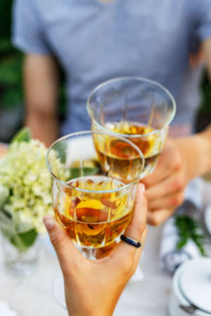 Happy family having dinner at the summer garden party and clinking drinks. People say toast and drink. Festive family dinner in the backyard. Male and female hands holding glasses of wine. Lifestyleの写真素材