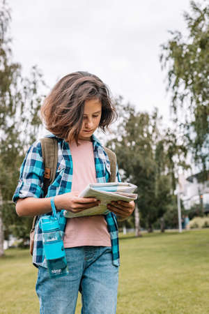 Hipster young girl travel around the city. Cute brunette teen girl looks at the map. Traveling in summer vacation. vertical shotの写真素材
