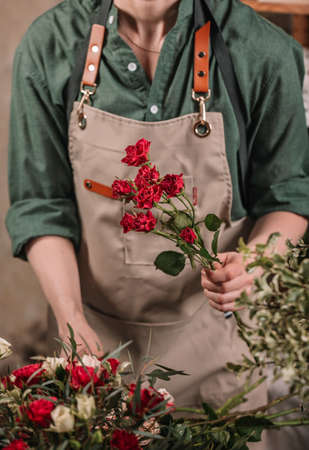 Florist make gift bouquets. Graceful female hands make a beautiful bouquet. Florist workplace. Small business concept. flowers and accessories. vertical shotの写真素材