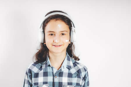 Portrait of a positive smiling teenage girl. Cute pretty girl in white headphones on a white background. copyspace. Teenager stock photoの写真素材