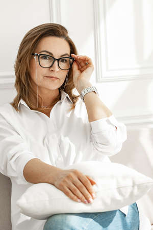Portrait of an attractive middle-aged woman in stylish glasses. Pretty woman in white cotton shirt...