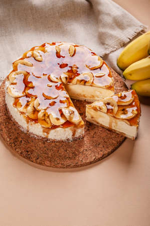 Banana cheesecake with caramel on a beige background. Homemade delicious pastries. vertical shot. Sweet tasty dessert. copy spaceの写真素材