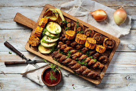 Assorted kebabs with grilled vegetables and herbs. Appetizing fried meat, corn, zucchini and...