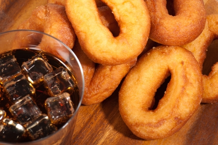 Oil donuts and cola with ice on a wooden plate.の写真素材