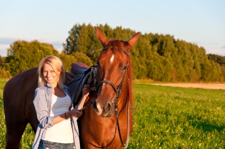 Young girl walking with a horse in the field.の写真素材