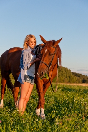 Young girl walking with a horse in the field.の写真素材