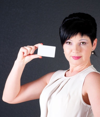 serious business woman with blank card over dark backgroundの写真素材