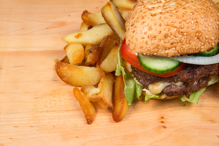 Fast food hamburger and french fries on a wooden plateの写真素材