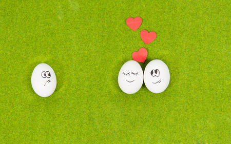 funny eggs in love and one jealous egg on a green grass. summer romanticの写真素材