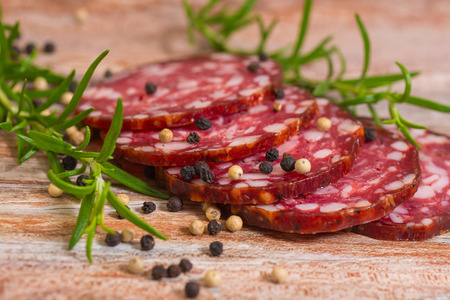 salami slices with pepper and rosemary on wooden backgroundの写真素材