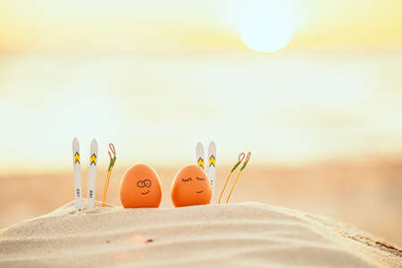 easter funny eggs relaxing on a beach.の写真素材