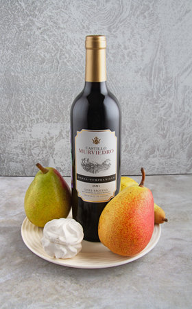 a bottle of wine on a plate with pears and marshmallows, light backgroundのeditorial素材