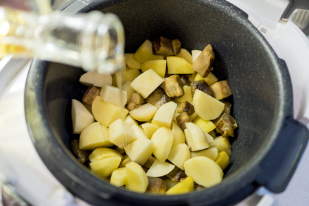 Vegetable oil is poured into a pot of potatoesの写真素材