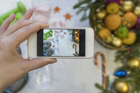 A basket of fruit and sweets stands against sports shoes and dumbbells. New life from the new year 2018. All is photographed through a mobile phone.の写真素材